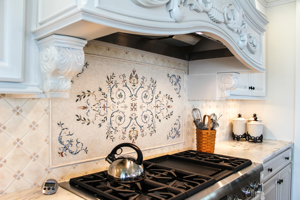 This is an example of a large traditional l-shaped open plan kitchen in New York with a drop-in sink, raised-panel cabinets, white cabinets, marble benchtops, stainless steel appliances, ceramic floors, with island, multi-coloured splashback and mosaic tile splashback.