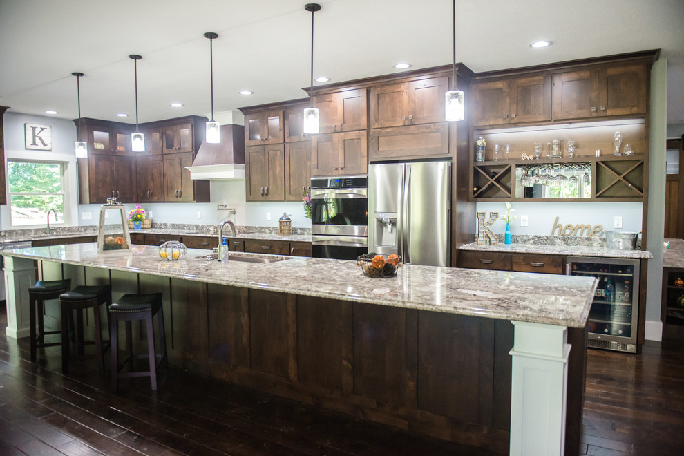 Inspiration for a transitional l-shaped open concept kitchen remodel with an undermount sink, shaker cabinets, dark wood cabinets, granite countertops, stainless steel appliances, an island and multicolored countertops