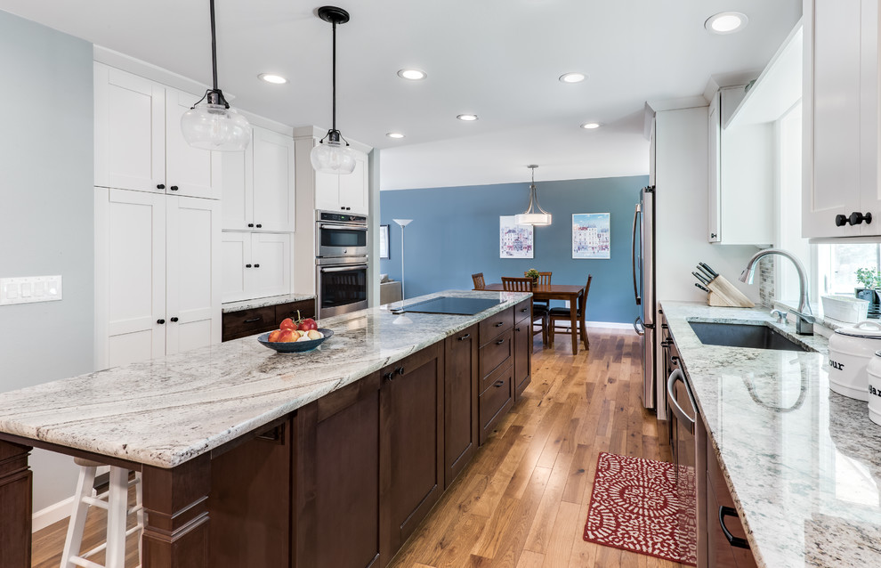 Inspiration for a mid-sized transitional galley medium tone wood floor and brown floor eat-in kitchen remodel in Denver with an undermount sink, shaker cabinets, white cabinets, granite countertops, blue backsplash, glass tile backsplash, stainless steel appliances, an island and beige countertops