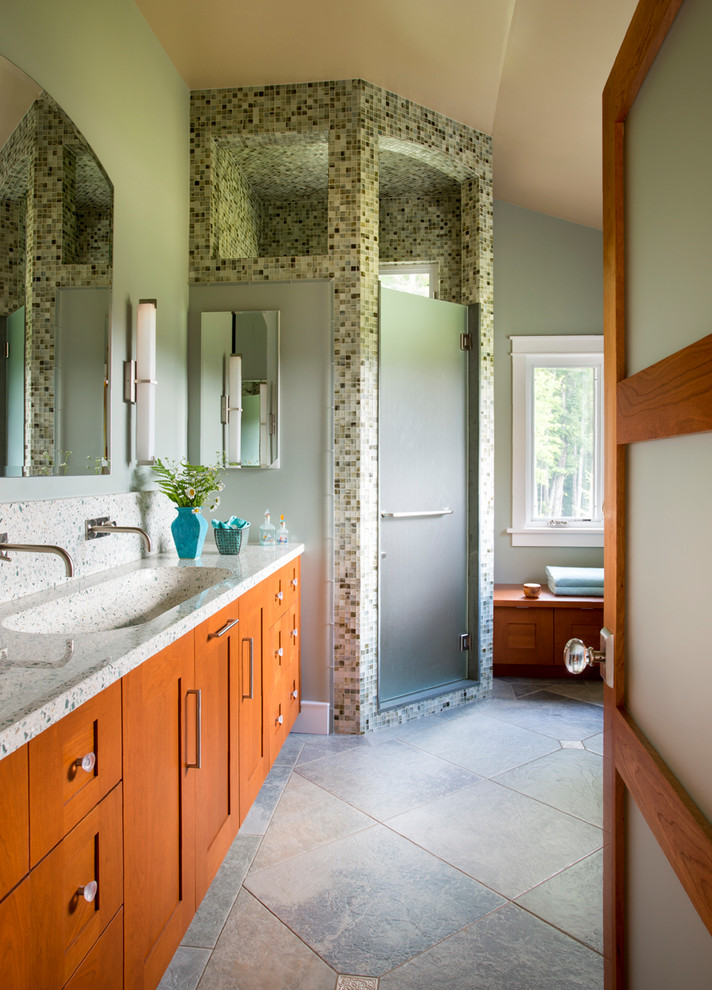 This is an example of a mid-sized modern master bathroom in Jacksonville with recessed-panel cabinets, medium wood cabinets, green tile, green walls, porcelain floors, a corner shower, glass tile, an integrated sink, terrazzo benchtops, green floor, a hinged shower door and multi-coloured benchtops.