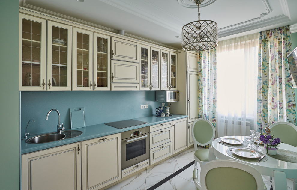 This is an example of a transitional single-wall eat-in kitchen in Moscow with a drop-in sink, raised-panel cabinets, beige cabinets, blue splashback, no island, blue benchtop, stainless steel appliances and white floor.