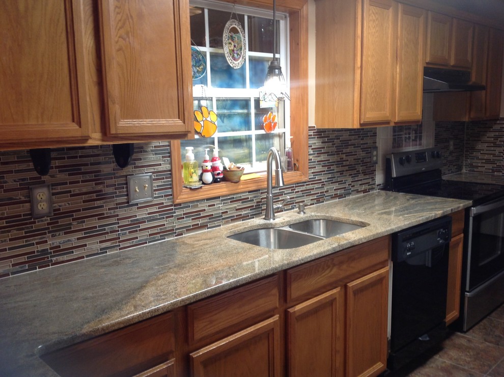 Eat-in kitchen - l-shaped eat-in kitchen idea with an undermount sink, flat-panel cabinets, brown backsplash, glass tile backsplash, stainless steel appliances and a peninsula