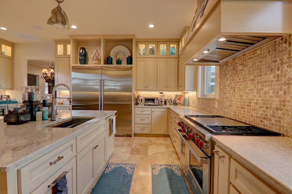 This is an example of a large transitional u-shaped eat-in kitchen in Dallas with an undermount sink, beige cabinets, granite benchtops, beige splashback, mosaic tile splashback, stainless steel appliances, travertine floors, with island, beige floor, beige benchtop and recessed-panel cabinets.