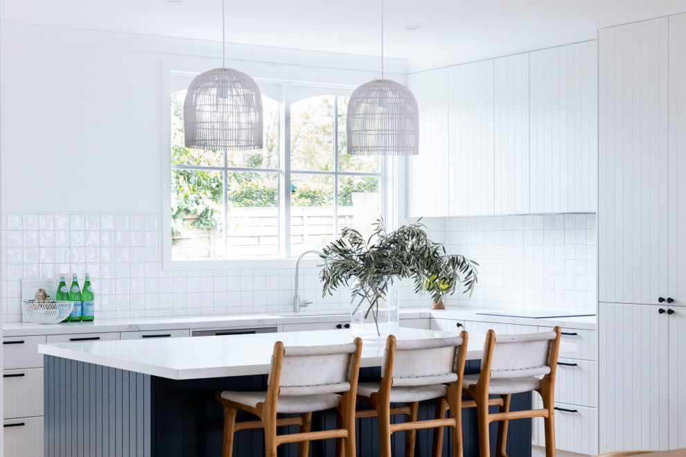 Inspiration for a contemporary l-shaped kitchen in Melbourne with an undermount sink, flat-panel cabinets, white cabinets, panelled appliances, medium hardwood floors, with island, brown floor and white benchtop.