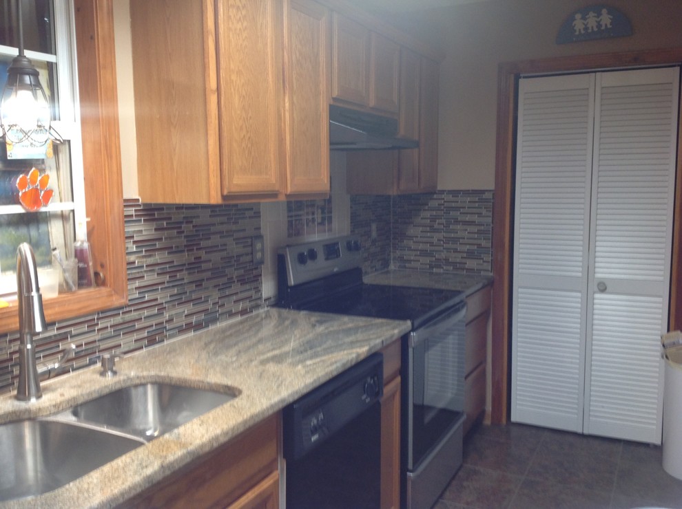 L-shaped eat-in kitchen photo with an undermount sink, flat-panel cabinets, brown backsplash, glass tile backsplash, stainless steel appliances and a peninsula