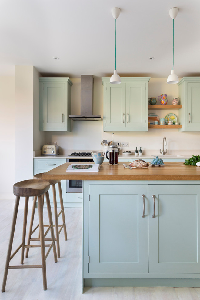 Photo of a large transitional kitchen in London with a single-bowl sink, blue cabinets, solid surface benchtops, light hardwood floors, with island, beige floor, beige benchtop, shaker cabinets, beige splashback and stainless steel appliances.