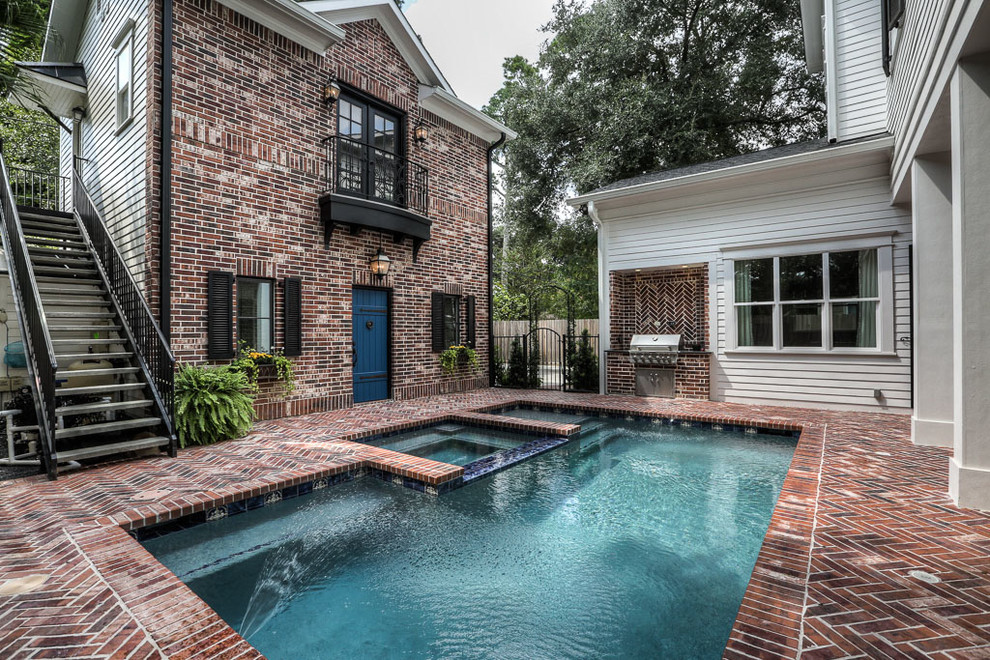 This is an example of a large traditional backyard rectangular lap pool in Houston with a hot tub and brick pavers.