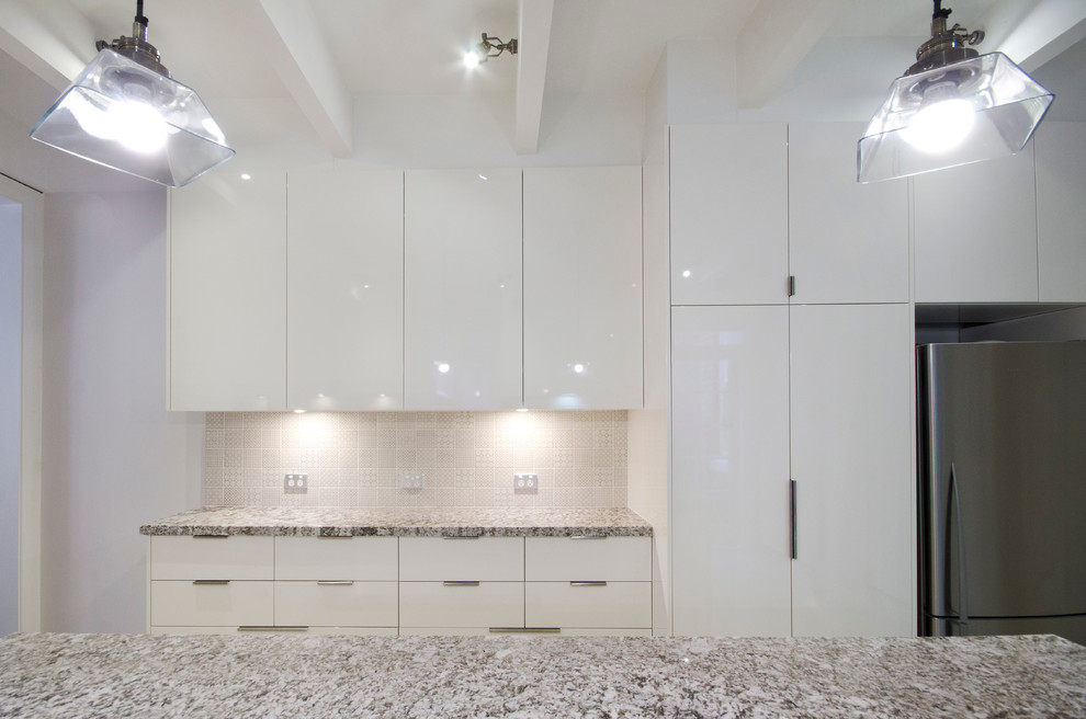 Photo of a mid-sized contemporary galley separate kitchen in Melbourne with an undermount sink, flat-panel cabinets, beige cabinets, granite benchtops, beige splashback, ceramic splashback, stainless steel appliances, porcelain floors, with island and beige floor.