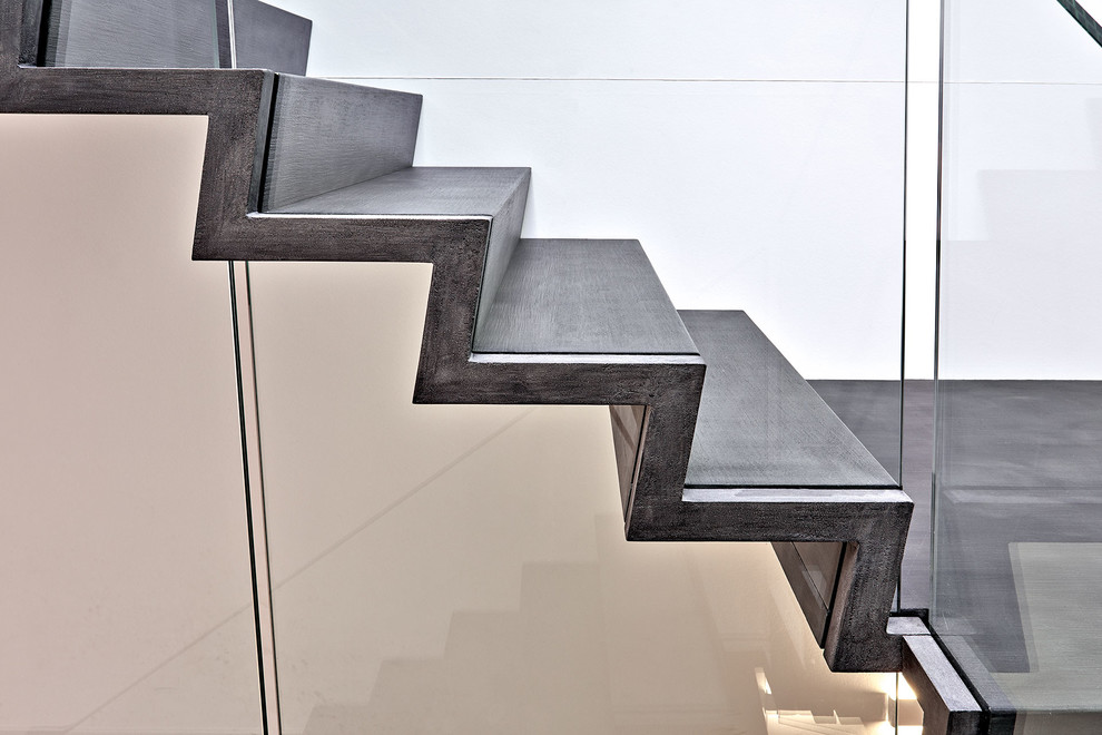 Пример оригинального дизайна: большая изогнутая лестница в современном стиле с стеклянными перилами