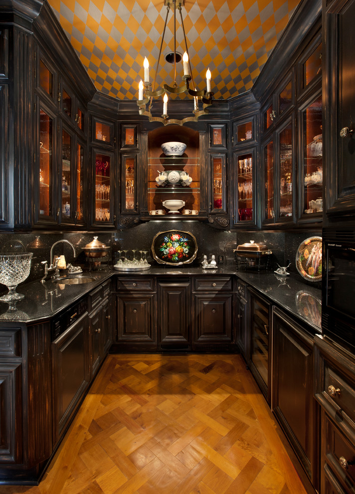 This is an example of a small mediterranean u-shaped kitchen pantry in San Francisco with an undermount sink, glass-front cabinets, black cabinets, black splashback, medium hardwood floors, granite benchtops, no island and panelled appliances.