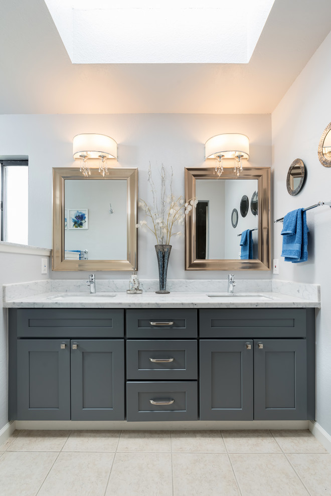 This is an example of a large transitional master bathroom in Other with shaker cabinets, grey cabinets, an alcove shower, a two-piece toilet, white tile, marble, beige walls, travertine floors, an undermount sink, quartzite benchtops, beige floor, a sliding shower screen and white benchtops.