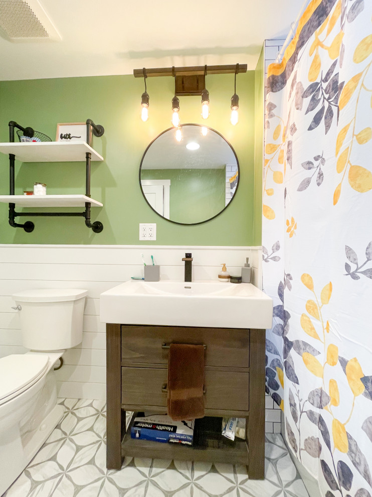 This is an example of a mid-sized arts and crafts kids bathroom in Chicago with recessed-panel cabinets, medium wood cabinets, an alcove tub, a shower/bathtub combo, a two-piece toilet, white tile, porcelain tile, green walls, ceramic floors, an integrated sink, solid surface benchtops, beige floor, a shower curtain, white benchtops, a niche, a single vanity, a freestanding vanity, wood and wood walls.