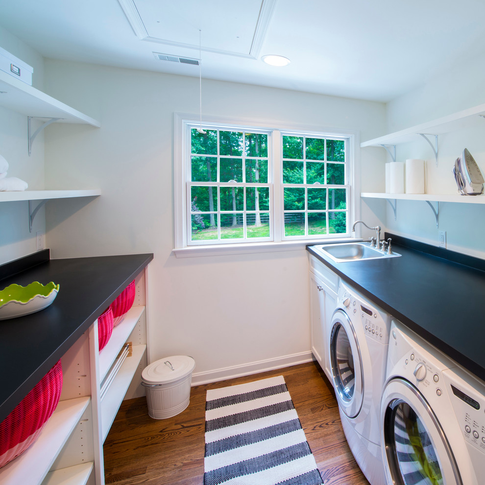 This is an example of a traditional laundry room in Baltimore with a drop-in sink, white cabinets and black benchtop.