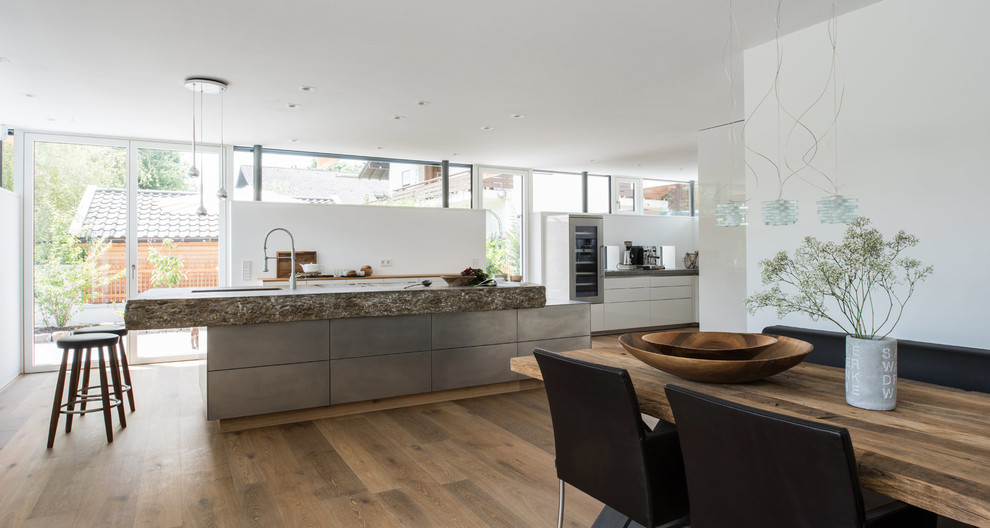 Design ideas for a large contemporary l-shaped eat-in kitchen in Munich with an integrated sink, flat-panel cabinets, white cabinets, limestone benchtops, white splashback and with island.