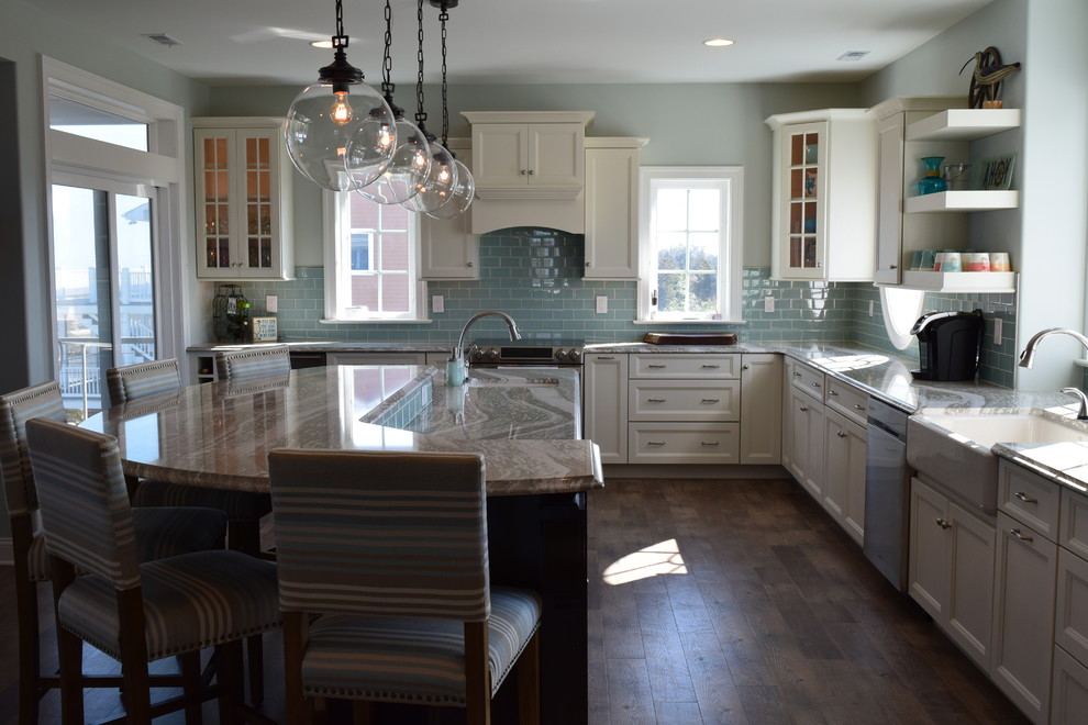 Beach style medium tone wood floor kitchen photo with a double-bowl sink, recessed-panel cabinets, white cabinets, quartz countertops, blue backsplash, ceramic backsplash, stainless steel appliances and an island