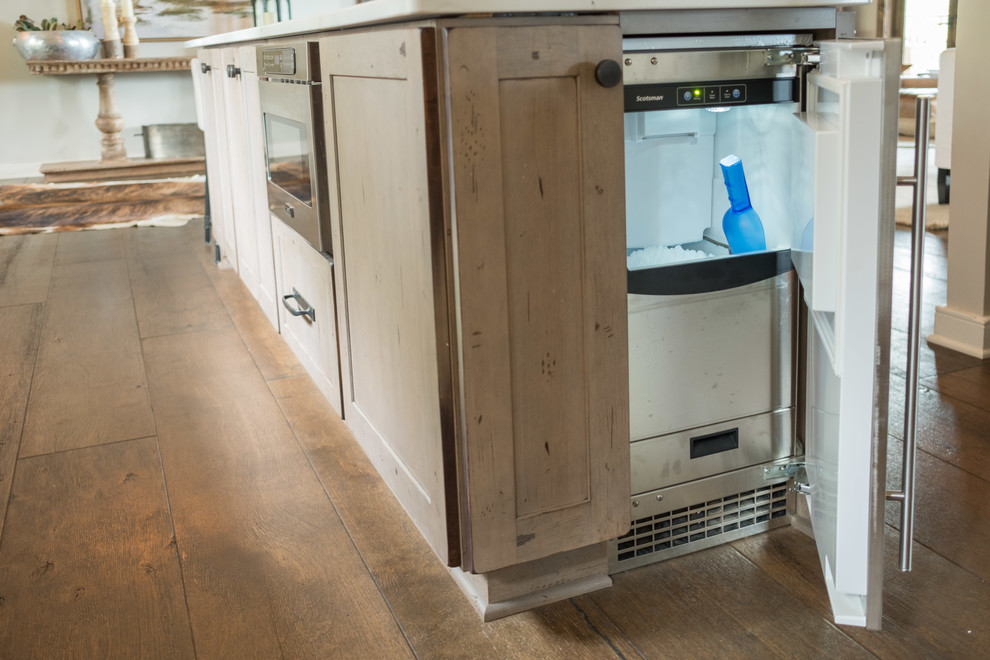 Large transitional galley dark wood floor and brown floor open concept kitchen photo with a farmhouse sink, shaker cabinets, quartz countertops, brown backsplash, brick backsplash, stainless steel appliances and an island