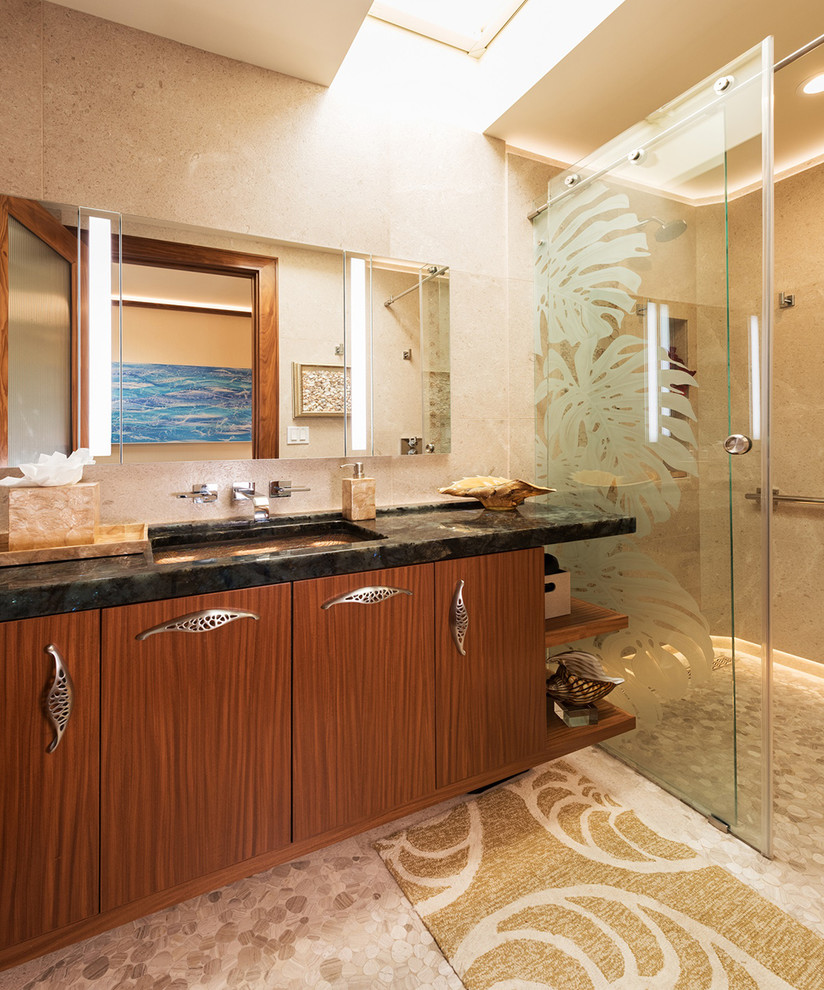 Inspiration for a tropical kids bathroom in Hawaii with flat-panel cabinets, medium wood cabinets, a curbless shower, a wall-mount toilet, beige tile, limestone, beige walls, limestone floors, quartzite benchtops, beige floor, a sliding shower screen, blue benchtops and an undermount sink.