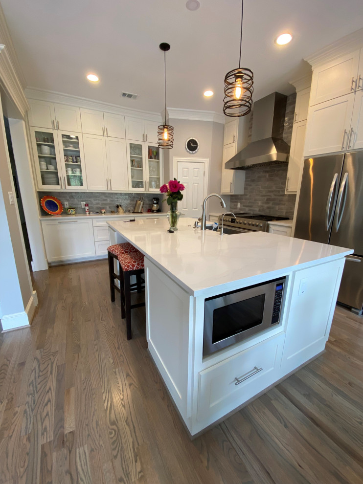 Design ideas for a large transitional u-shaped eat-in kitchen in Dallas with a farmhouse sink, shaker cabinets, white cabinets, quartzite benchtops, grey splashback, porcelain splashback, stainless steel appliances, medium hardwood floors, with island, grey floor and multi-coloured benchtop.