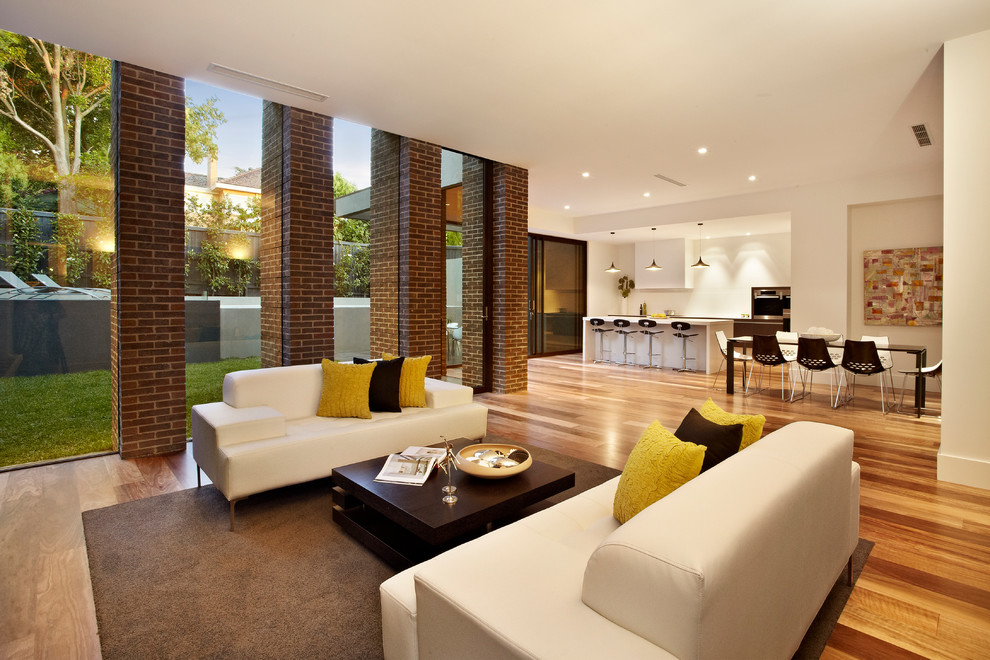 This is an example of a contemporary formal open concept living room in Melbourne with white walls, medium hardwood floors, no fireplace and no tv.