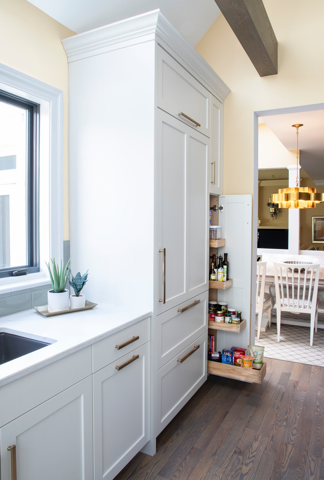 Example of a large transitional u-shaped medium tone wood floor kitchen design with an undermount sink, white cabinets, quartz countertops, gray backsplash, glass tile backsplash, stainless steel appliances, an island and white countertops