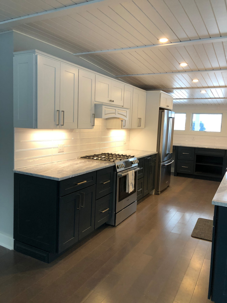 Large midcentury l-shaped eat-in kitchen in New York with a farmhouse sink, shaker cabinets, blue cabinets, granite benchtops, white splashback, subway tile splashback, stainless steel appliances, light hardwood floors, no island, grey floor, grey benchtop and wood.