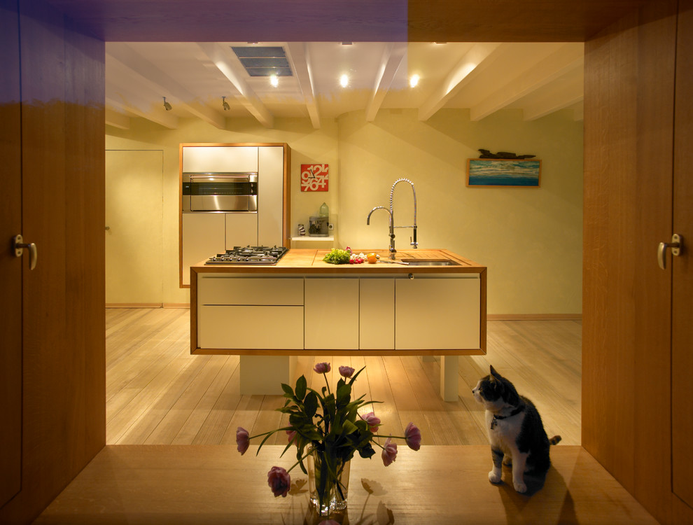 Offene, Einzeilige, Große Moderne Küche mit Kassettenfronten, Kücheninsel, integriertem Waschbecken, grauen Schränken, Arbeitsplatte aus Holz, Küchenrückwand in Gelb, Rückwand aus Steinfliesen, Küchengeräten aus Edelstahl, hellem Holzboden, braunem Boden und brauner Arbeitsplatte in Köln