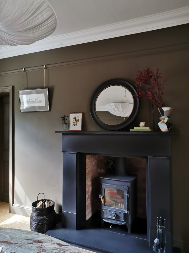 Exemple d'un salon chic de taille moyenne et fermé avec un mur marron, un sol en bois brun, une cheminée standard, un manteau de cheminée en pierre, aucun téléviseur et un sol beige.