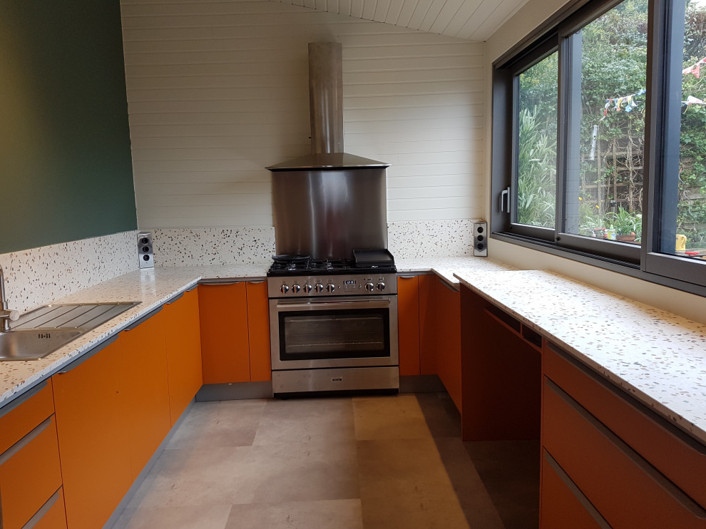 Photo of a mid-sized tropical u-shaped separate kitchen in Brest with a single-bowl sink, flat-panel cabinets, orange cabinets, terrazzo benchtops, multi-coloured splashback, stone slab splashback, stainless steel appliances, laminate floors, no island, grey floor and multi-coloured benchtop.