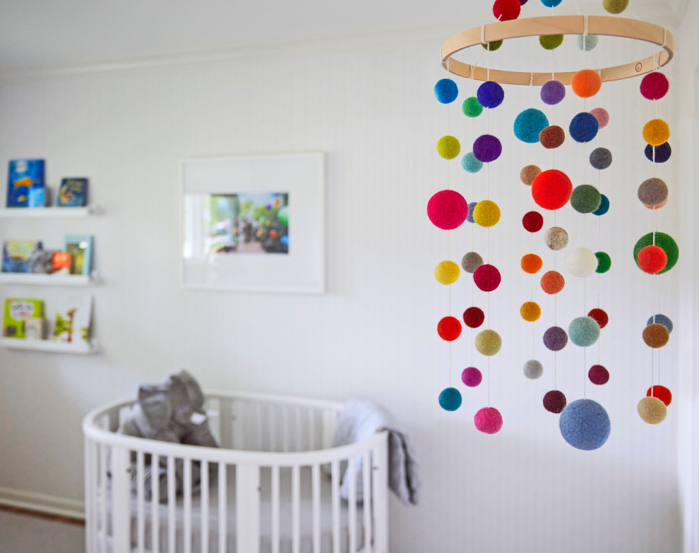 Cette image montre une chambre de bébé neutre traditionnelle de taille moyenne avec un mur multicolore, un sol en bois brun, un sol marron et du papier peint.