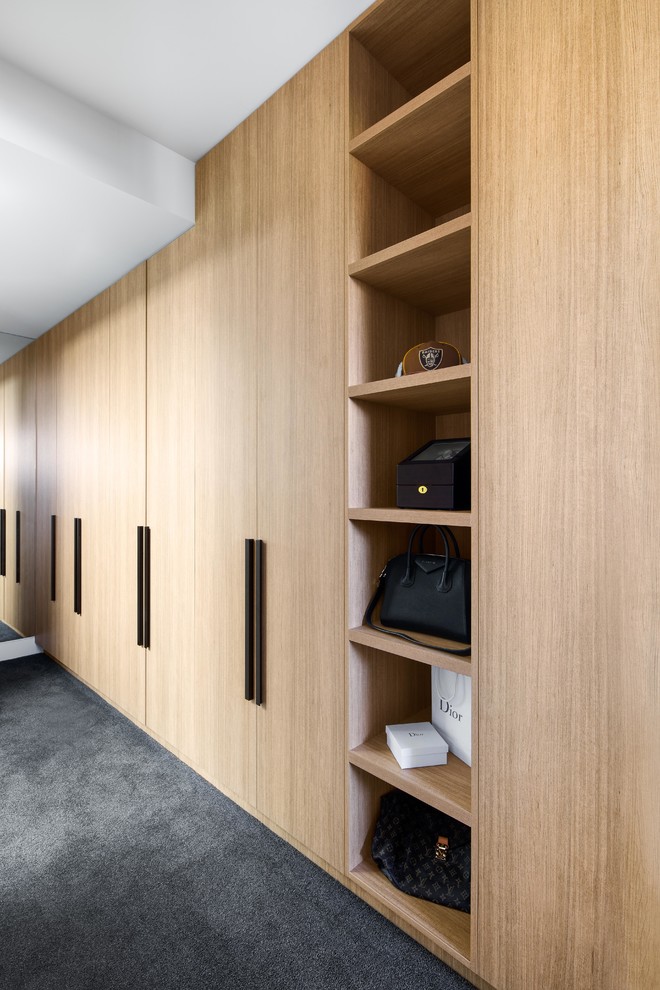 This is an example of a large contemporary walk-in wardrobe in Melbourne with open cabinets, medium wood cabinets, carpet and grey floor.