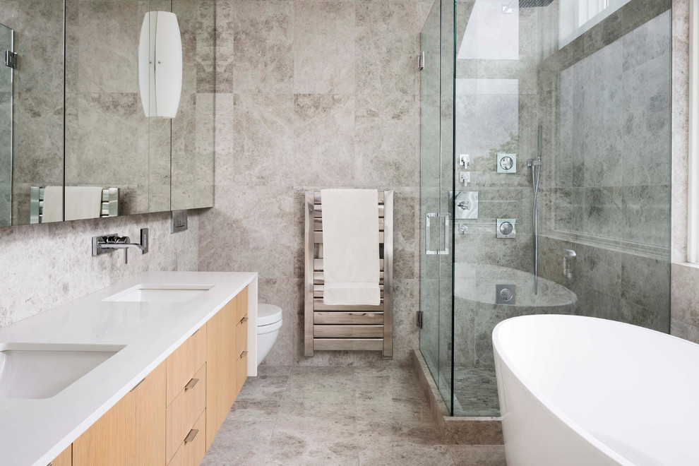 Contemporary bathroom in Vancouver with flat-panel cabinets, light wood cabinets, a freestanding tub, a corner shower, gray tile, an undermount sink and a hinged shower door.