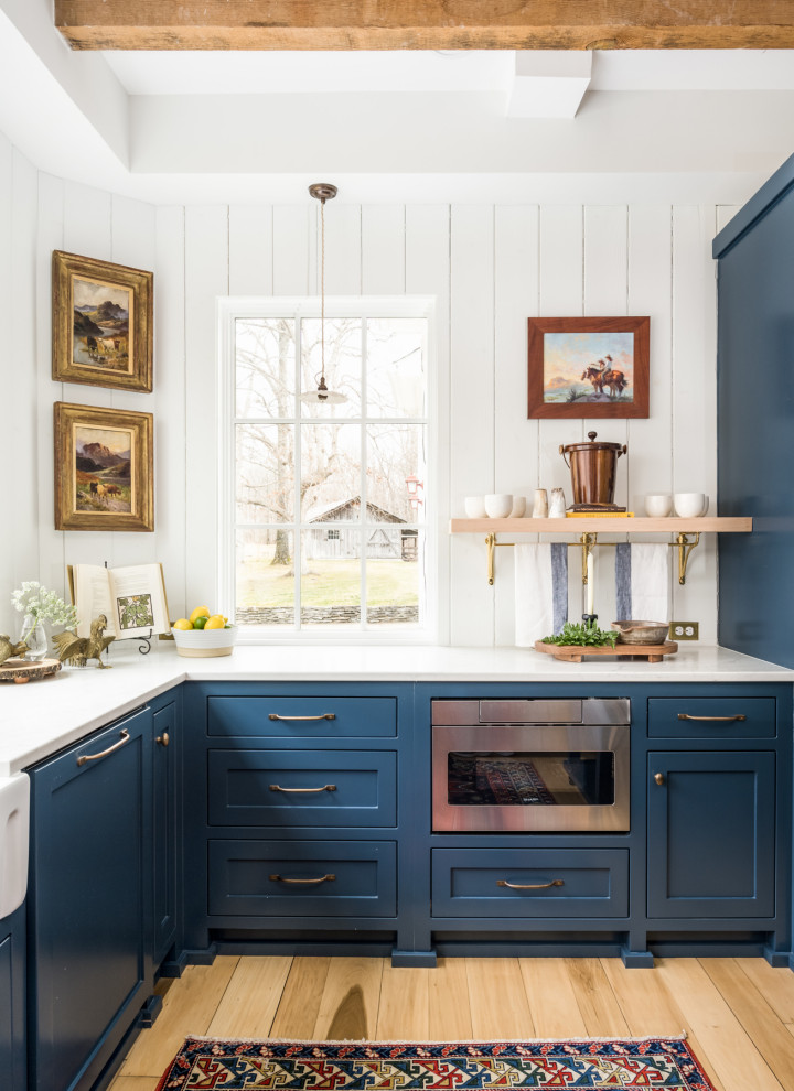ナッシュビルにある高級な中くらいなカントリー風のおしゃれなキッチン (エプロンフロントシンク、インセット扉のキャビネット、青いキャビネット、クオーツストーンカウンター、白いキッチンパネル、木材のキッチンパネル、シルバーの調理設備、淡色無垢フローリング、黄色い床、白いキッチンカウンター、表し梁) の写真