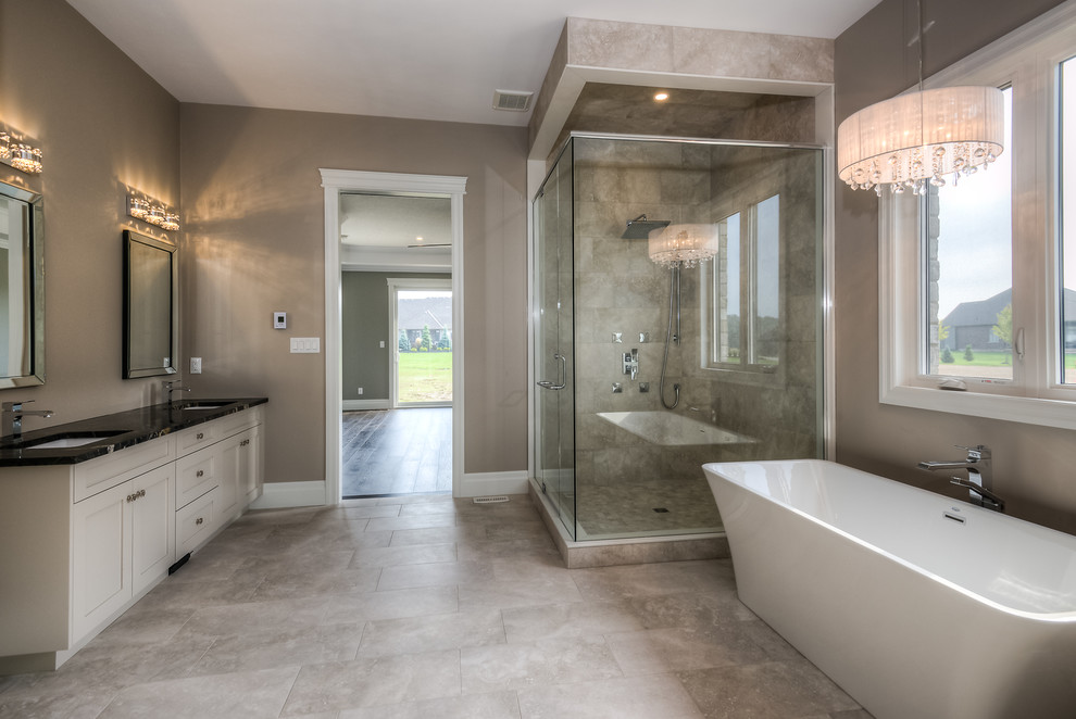 This is an example of a large traditional master bathroom in Other with shaker cabinets, beige cabinets, a freestanding tub, a corner shower, a two-piece toilet, beige walls, ceramic floors, an undermount sink, granite benchtops, beige floor and a hinged shower door.