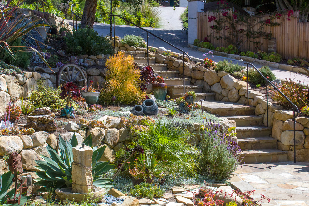 This is an example of a mid-sized contemporary front yard partial sun formal garden for spring in Santa Barbara with a garden path and natural stone pavers.