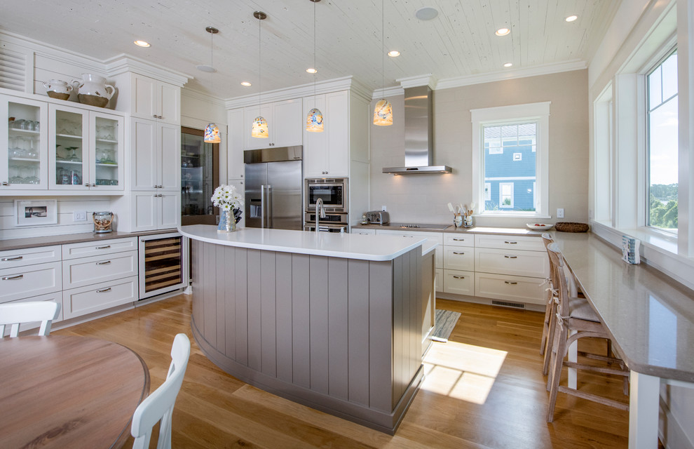 Design ideas for a beach style u-shaped kitchen in Other with shaker cabinets, white cabinets, stainless steel appliances, medium hardwood floors, with island, brown floor and grey benchtop.