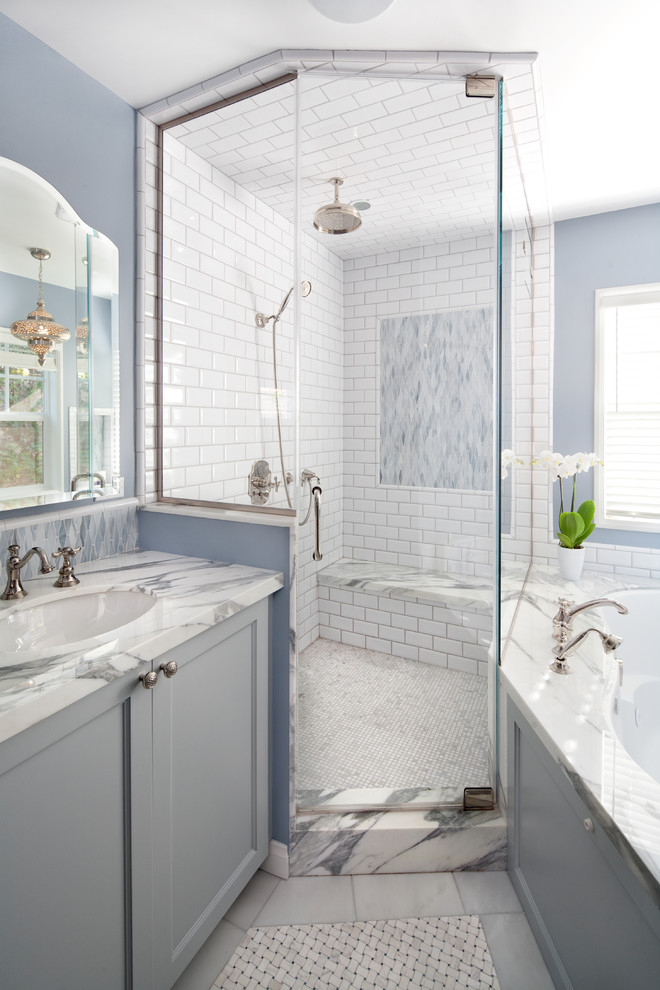 Large beach style master bathroom in Los Angeles with an undermount sink, grey cabinets, an undermount tub, a corner shower, white tile, subway tile, blue walls, marble benchtops, recessed-panel cabinets, marble floors and a shower seat.