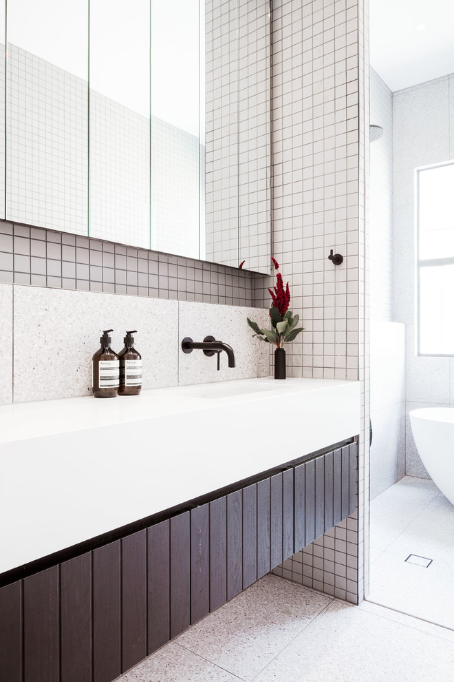 This is an example of a mid-sized contemporary master bathroom in Melbourne with black cabinets, a freestanding tub, an open shower, a wall-mount toilet, gray tile, mosaic tile, grey walls, terrazzo floors, an undermount sink, engineered quartz benchtops, grey floor, an open shower and white benchtops.