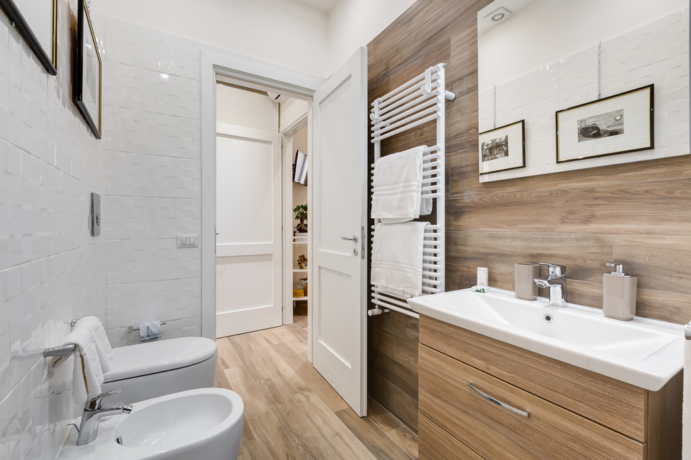Photo of a modern bathroom in Rome with flat-panel cabinets, a two-piece toilet, white tile, ceramic tile, white walls, medium hardwood floors and an integrated sink.