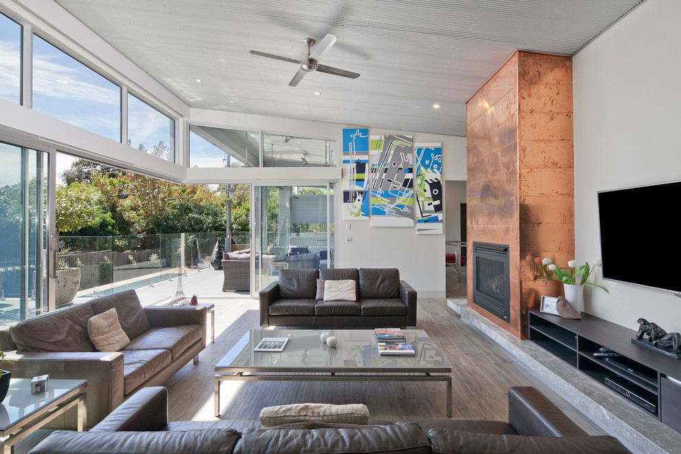 This is an example of a large contemporary open concept family room in Canberra - Queanbeyan with ceramic floors, a standard fireplace, a metal fireplace surround and a wall-mounted tv.