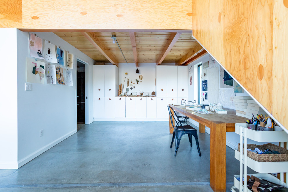 Идея дизайна: домашняя мастерская среднего размера в стиле лофт с белыми стенами, бетонным полом, отдельно стоящим рабочим столом, серым полом и балками на потолке