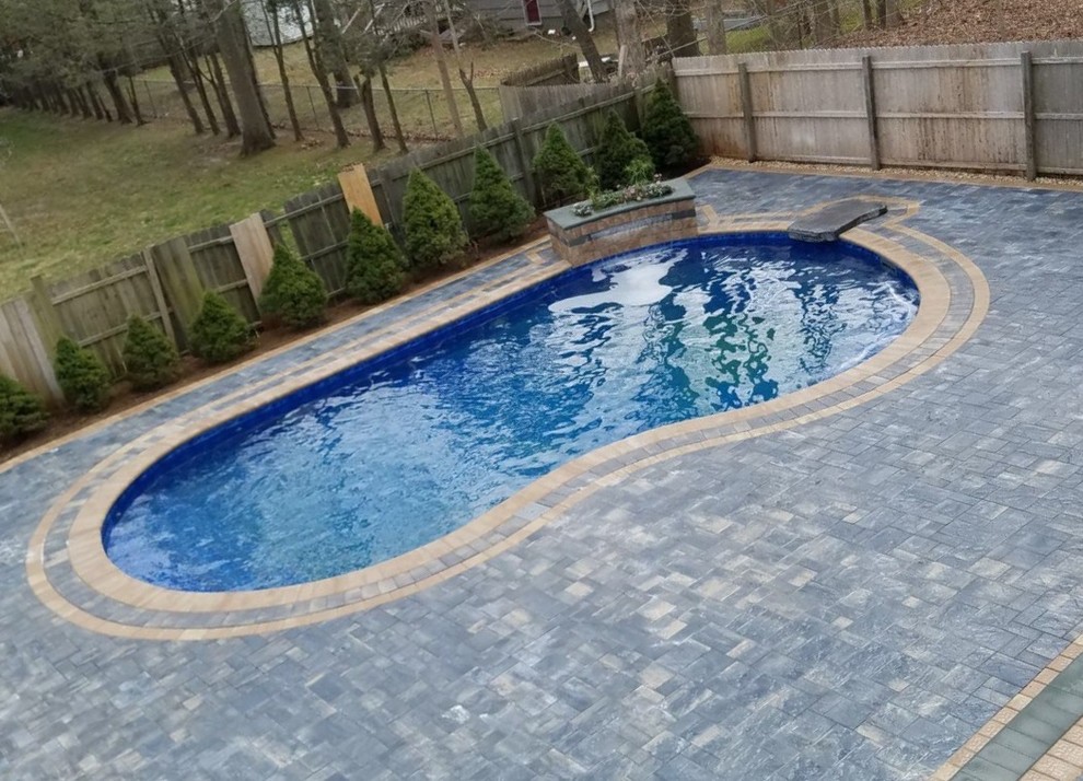Photo of a large beach style backyard custom-shaped natural pool in New York with concrete pavers.