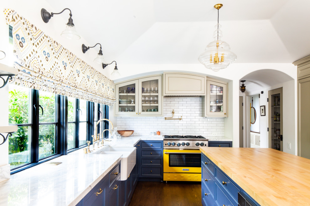 Mediterranean eat-in kitchen in Los Angeles with a farmhouse sink, recessed-panel cabinets, blue cabinets, marble benchtops, white splashback, terra-cotta splashback, coloured appliances, medium hardwood floors, with island, brown floor, white benchtop and coffered.