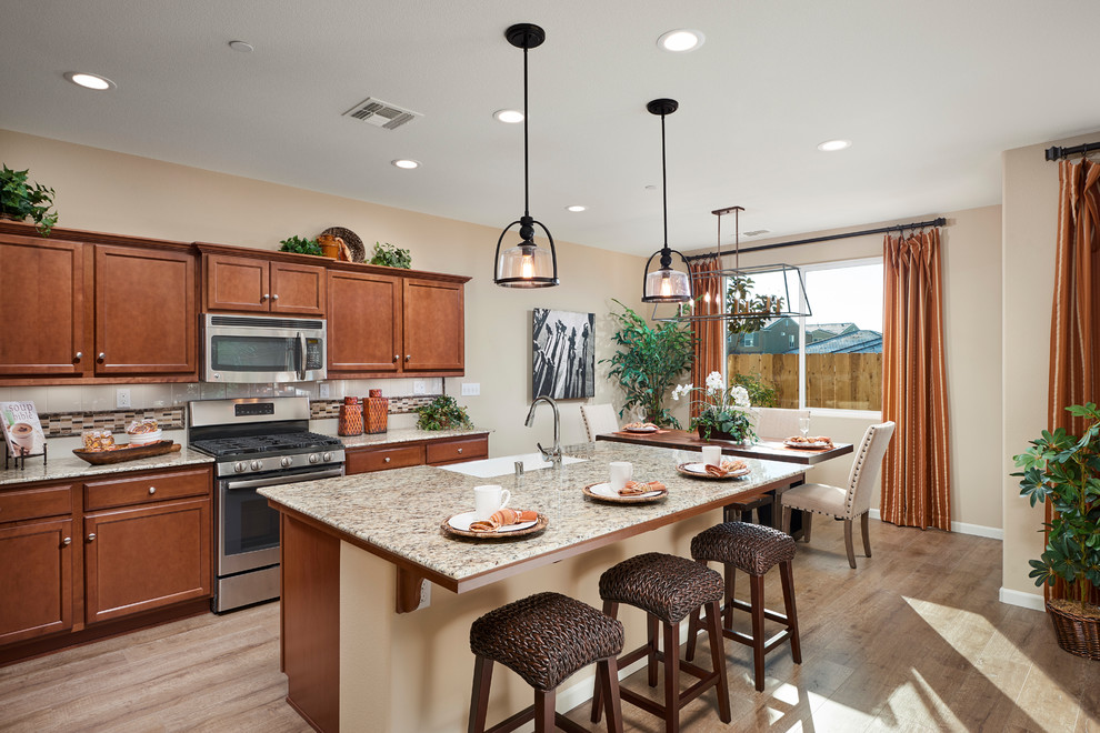 Example of a transitional kitchen design with a drop-in sink, medium tone wood cabinets, granite countertops, white backsplash, ceramic backsplash, stainless steel appliances and an island