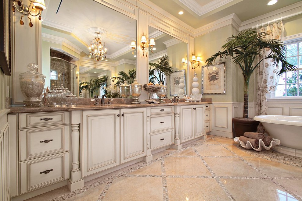 Photo of a large traditional master bathroom in Miami with raised-panel cabinets, white cabinets, a freestanding tub, green walls, ceramic floors, an undermount sink and granite benchtops.