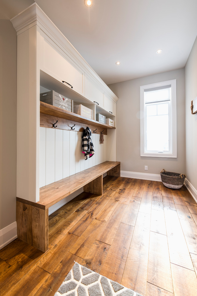 Photo of a large transitional mudroom in Toronto with white walls, medium hardwood floors and brown floor.
