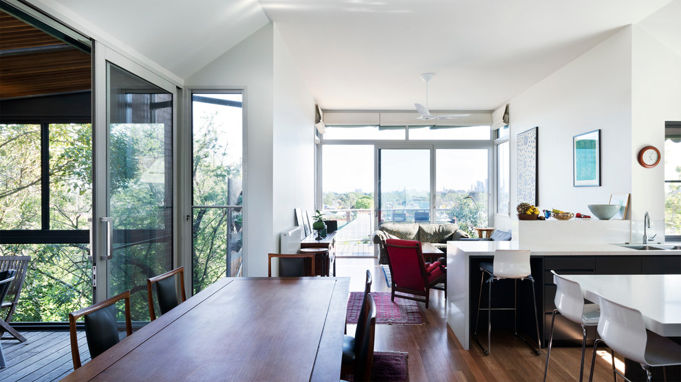 This is an example of a mid-sized contemporary open concept living room in Melbourne with white walls and medium hardwood floors.