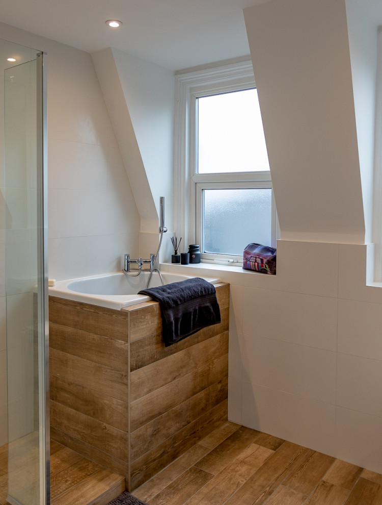 Mid-sized contemporary kids bathroom in London with white cabinets, a japanese tub, an open shower, a one-piece toilet, white tile, ceramic tile, white walls, cement tiles, granite benchtops, brown floor, a hinged shower door and black benchtops.