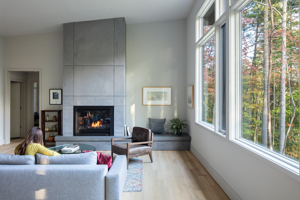 Mid-sized midcentury open concept living room in Other with white walls, medium hardwood floors, a standard fireplace, a plaster fireplace surround, no tv and brown floor.