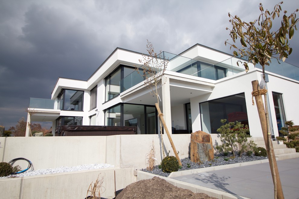 Photo of a large contemporary two-storey stucco white house exterior in Nuremberg with a flat roof and a green roof.