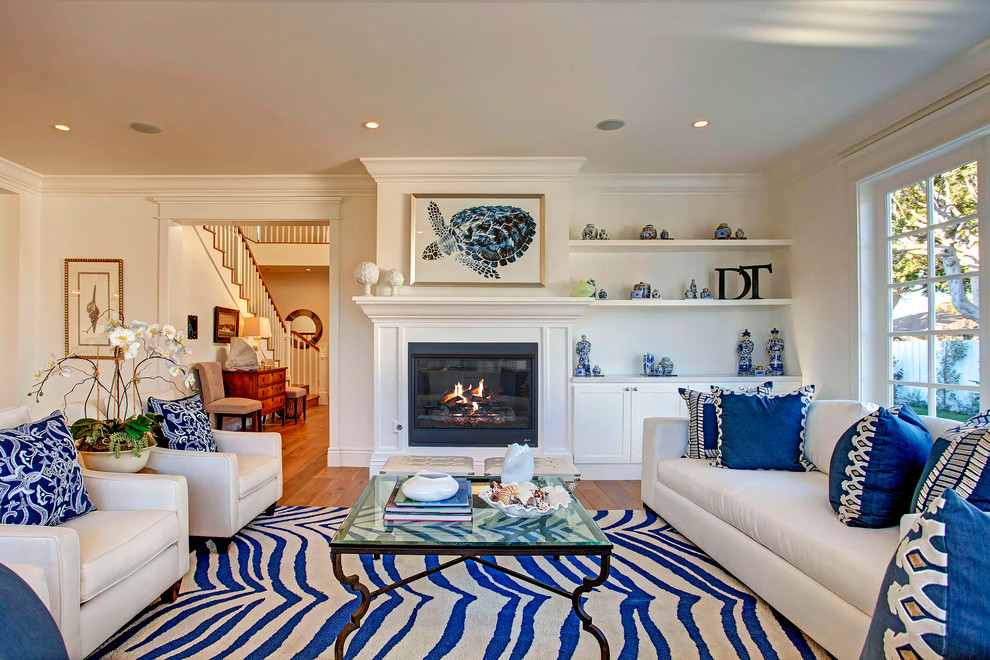 Design ideas for a beach style living room in Los Angeles with white walls, medium hardwood floors and a standard fireplace.